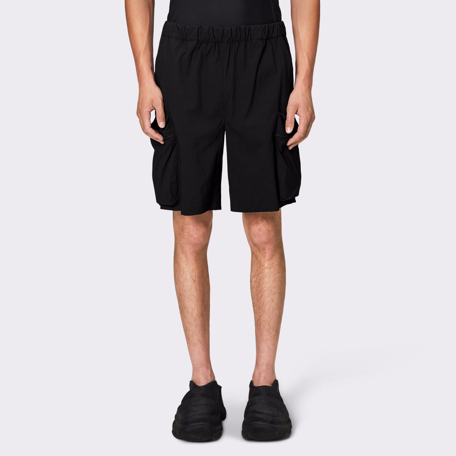 Calções pretos com cintura elástica e bolsos laterais em fundo cinza claro