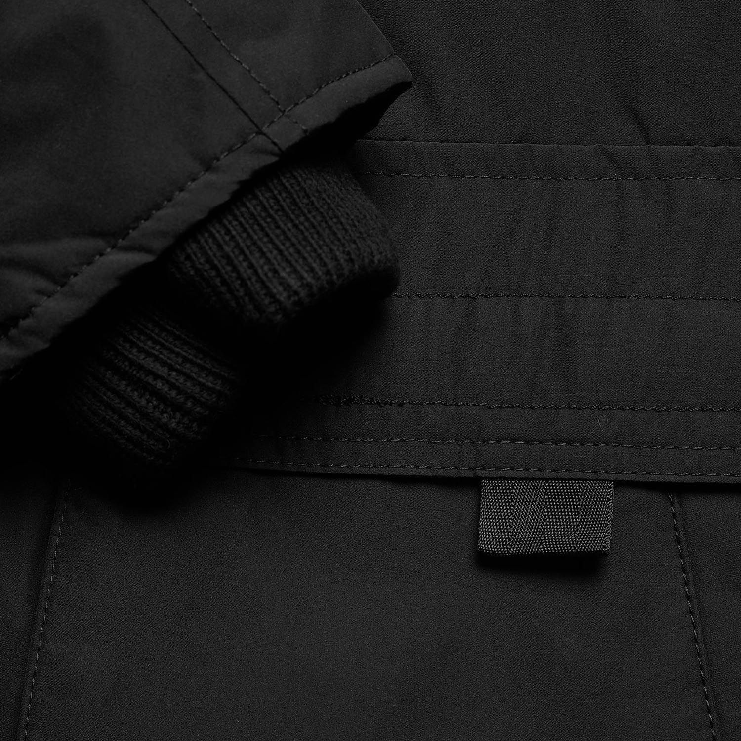 Punho de casaco preto com tecido canelado e costuras em detalhe