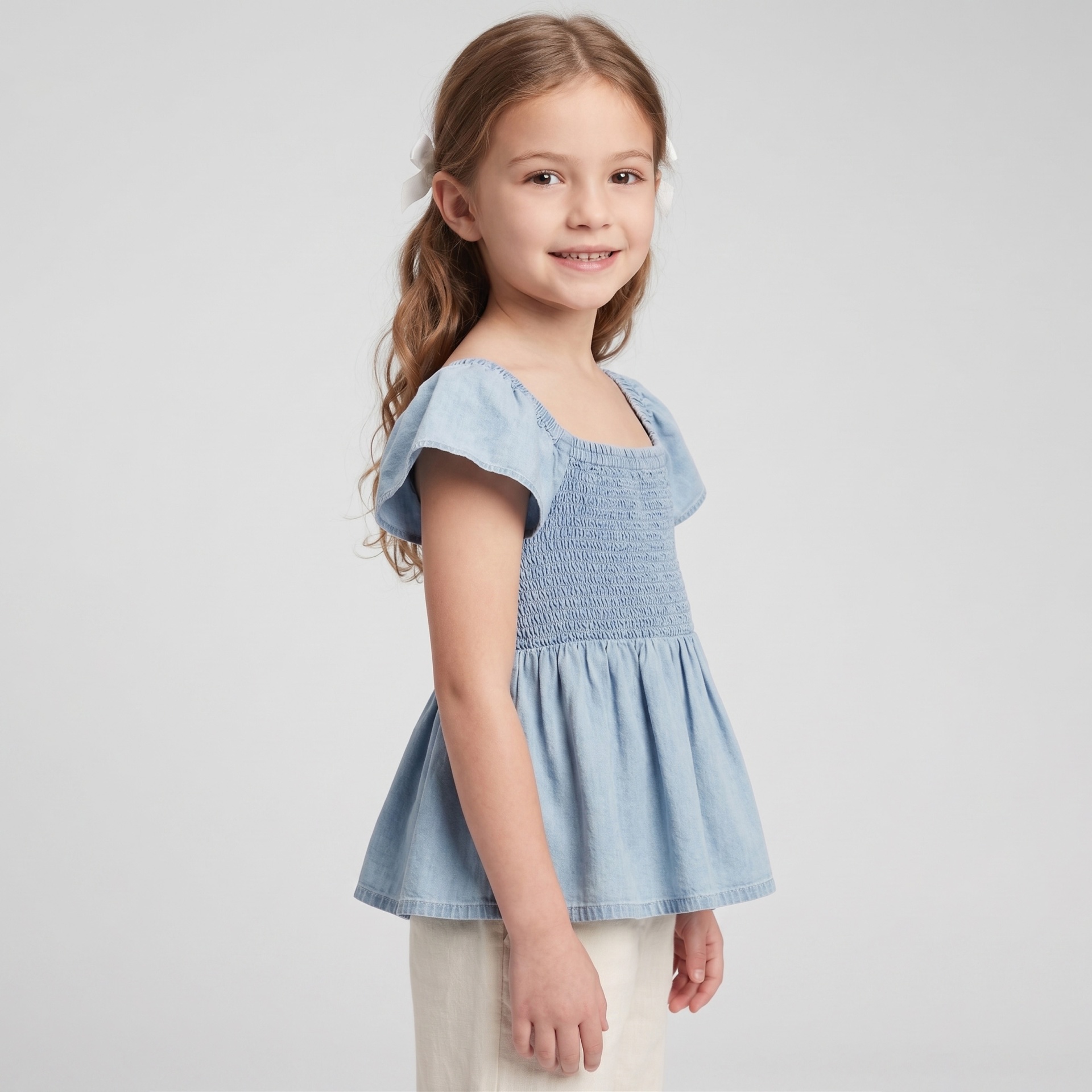 Menina vestindo vestido azul claro com mangas de babados e cabelo com laços brancos.