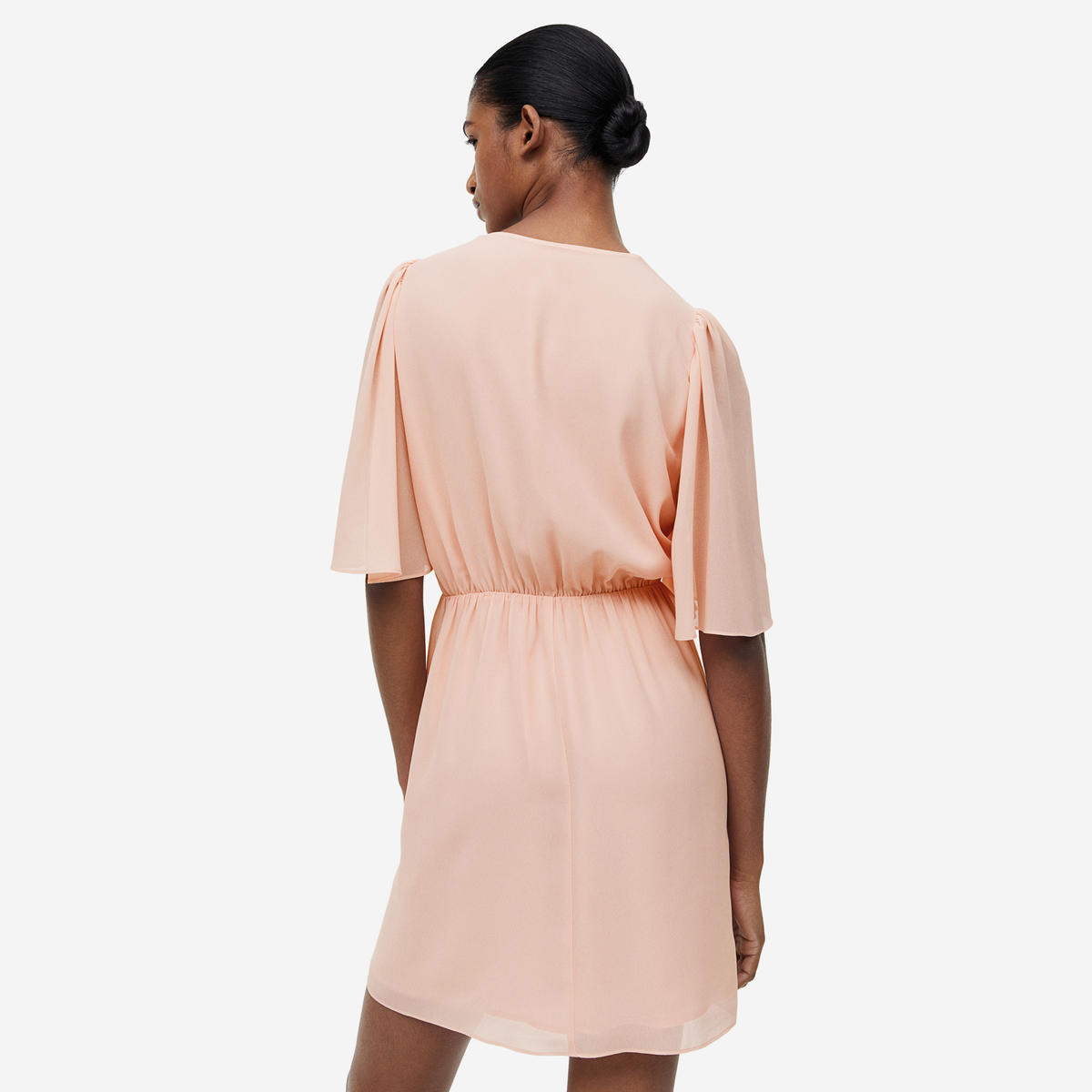 Vestido curto cor de pêssego com mangas largas visto de costas