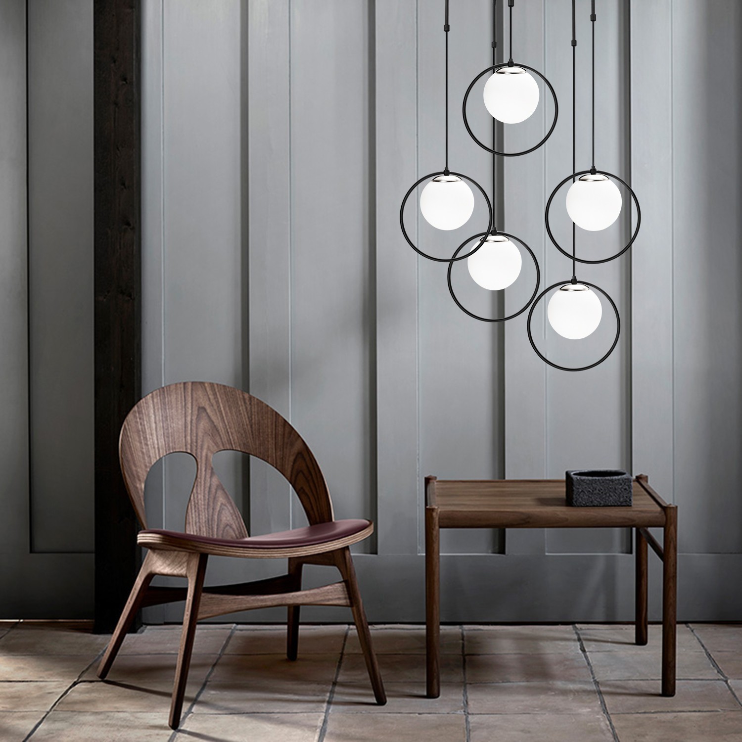 Cadeira de madeira com assento em couro, mesa de madeira escura e candeeiros pendurados com bolas brancas em aros pretos