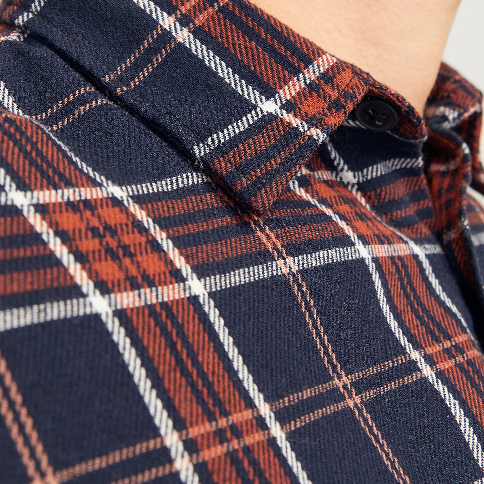 Camisa xadrez azul escuro com vermelho e branco, detalhe de botão preto na gola