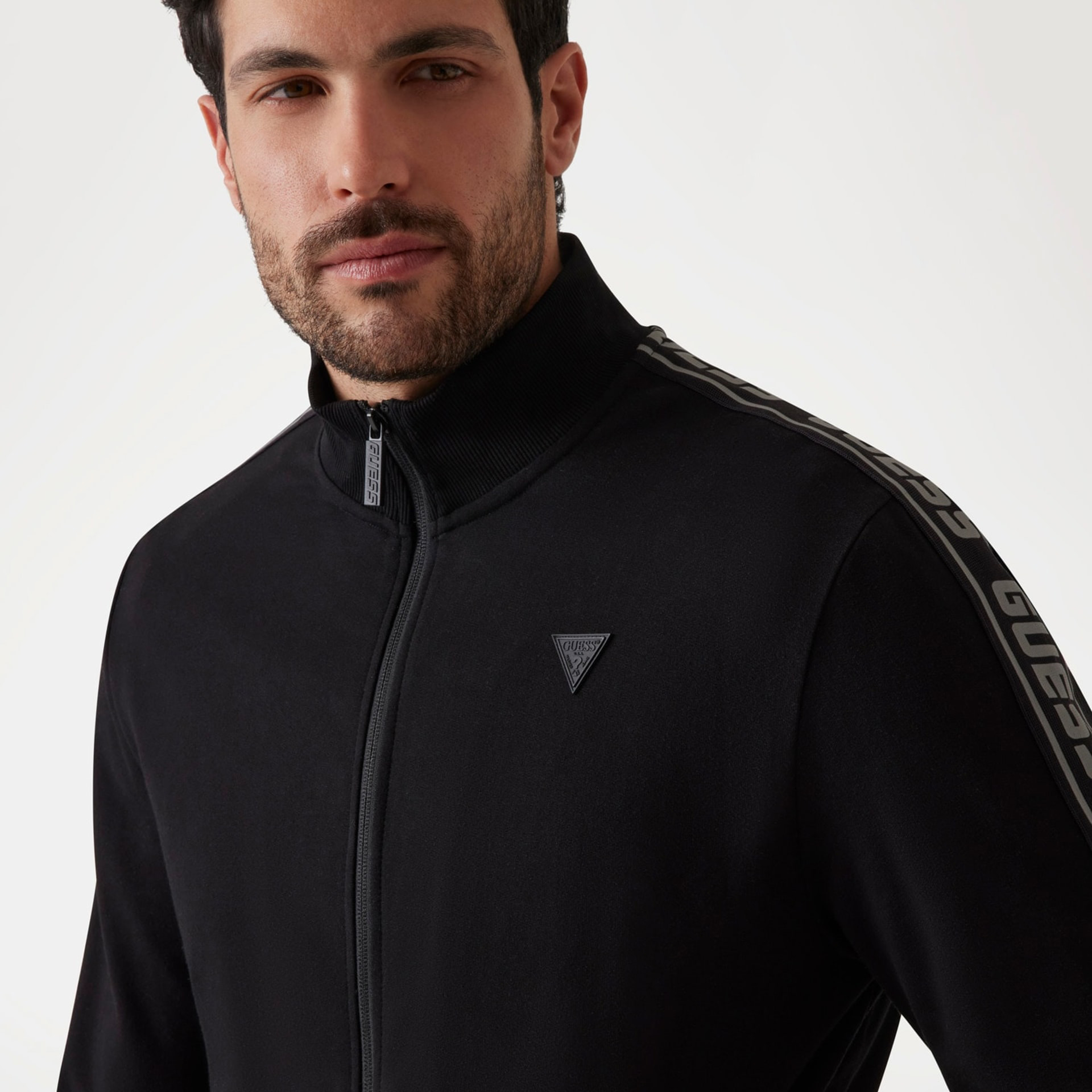 Casaco preto com fecho e logótipo triangular GUESS no peito e faixa GUESS nas mangas