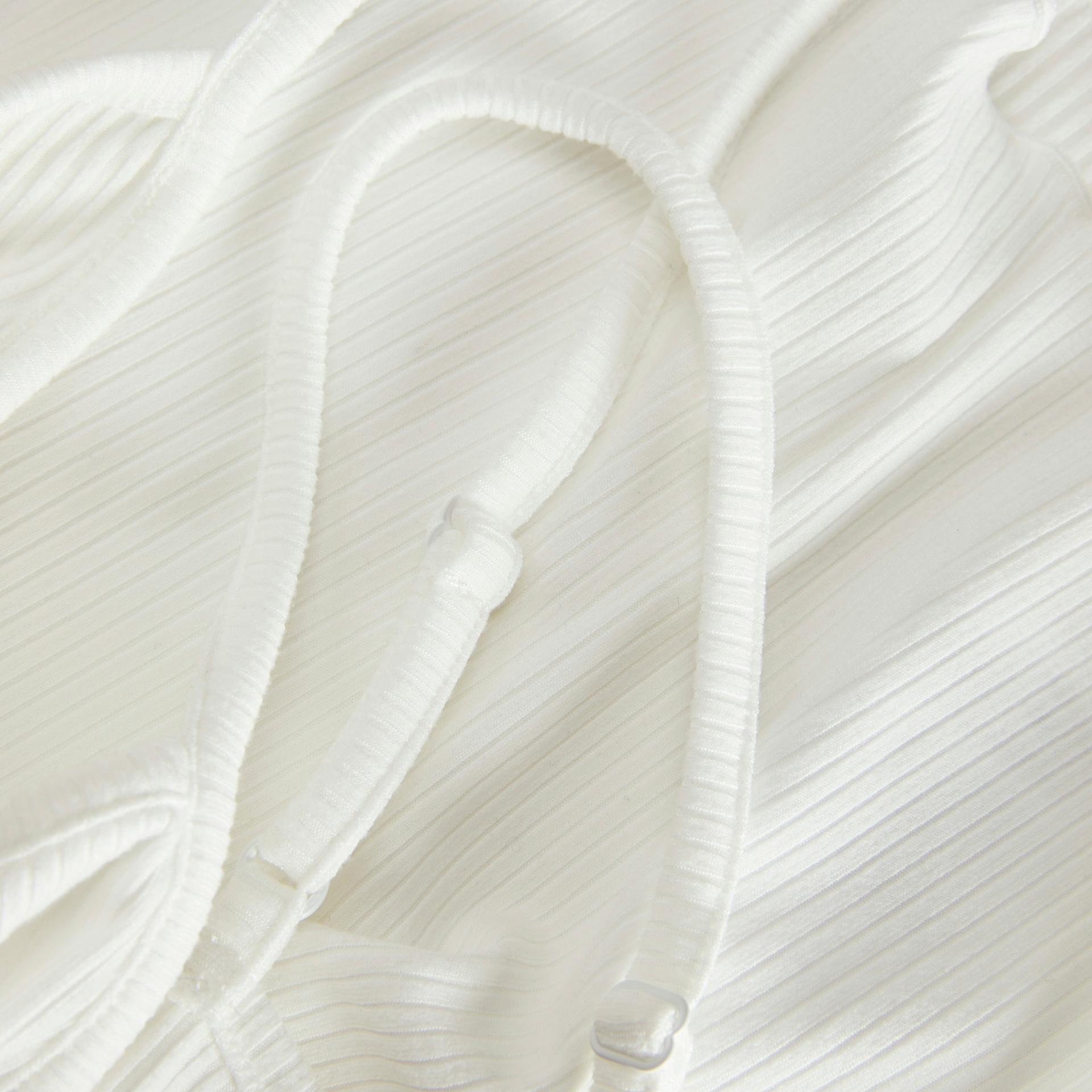 Tecido branco texturizado com alças ajustáveis em destaque