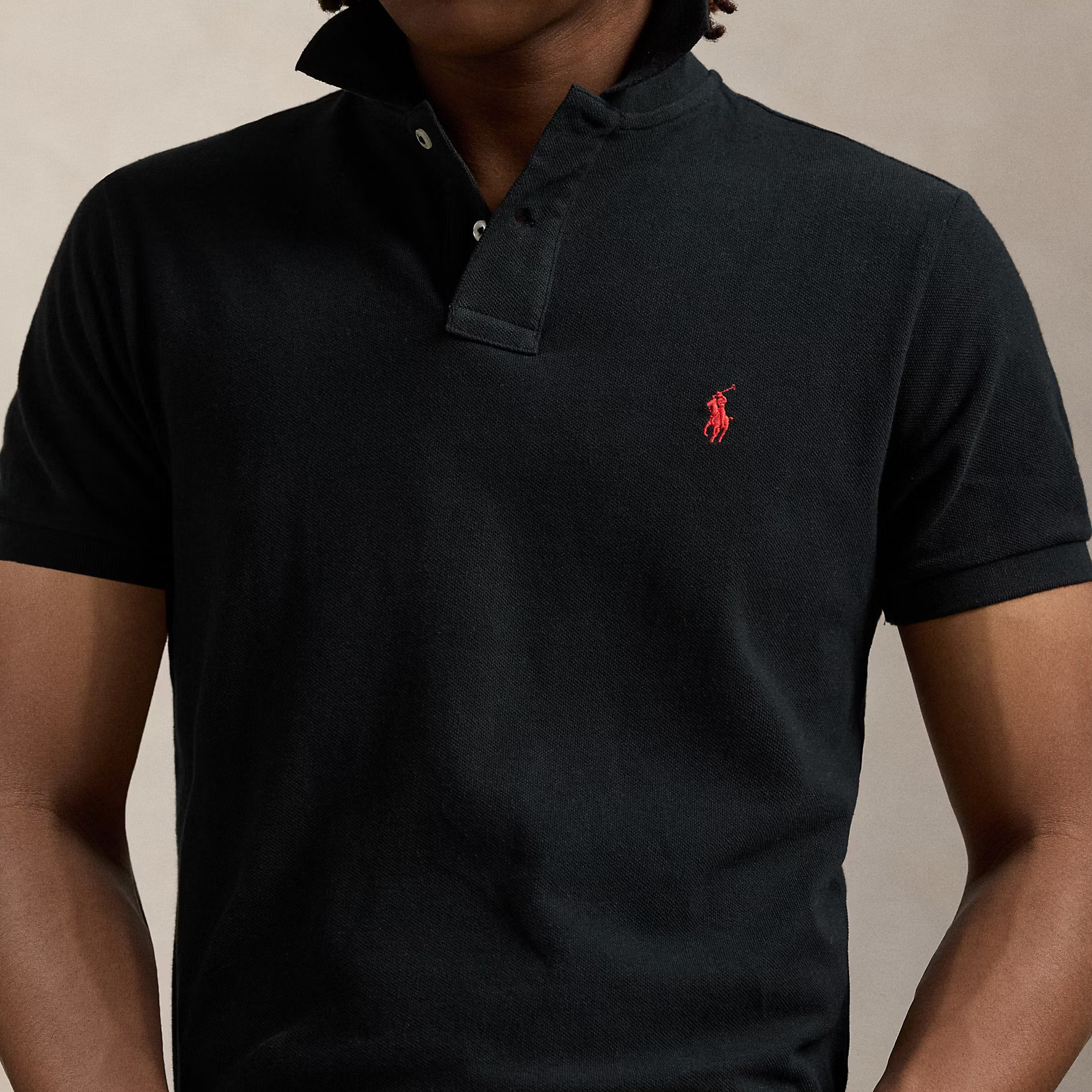 Polo preto com logo vermelho bordado no peito.