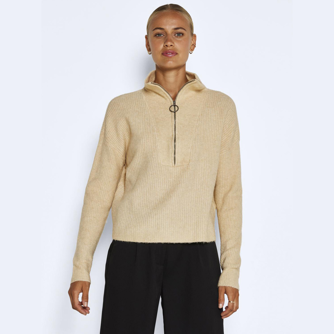 Camisola bege clara de malha com fecho de correr na parte frontal e calças pretas
