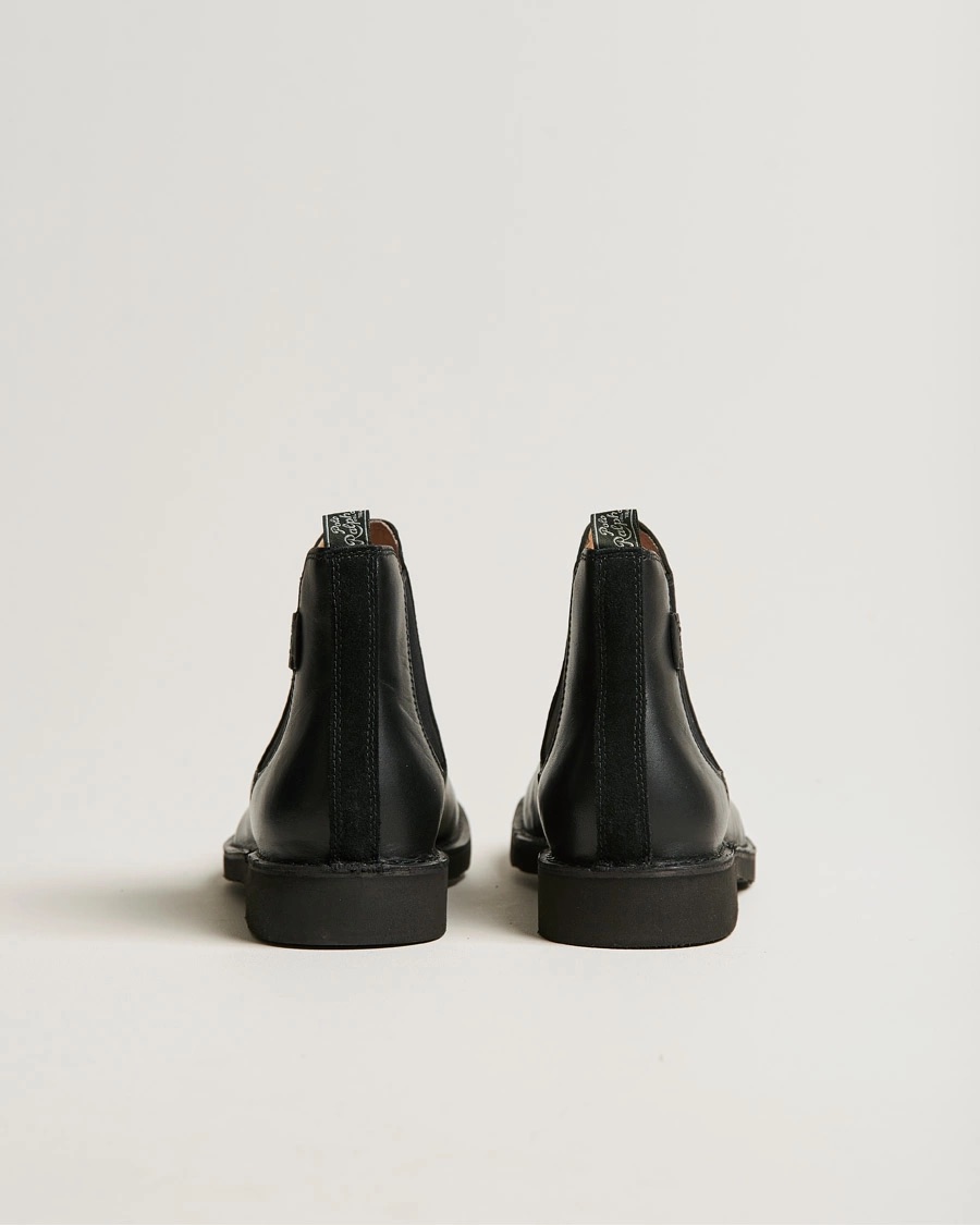 Botins pretos em pele vistos de trás com sola preta