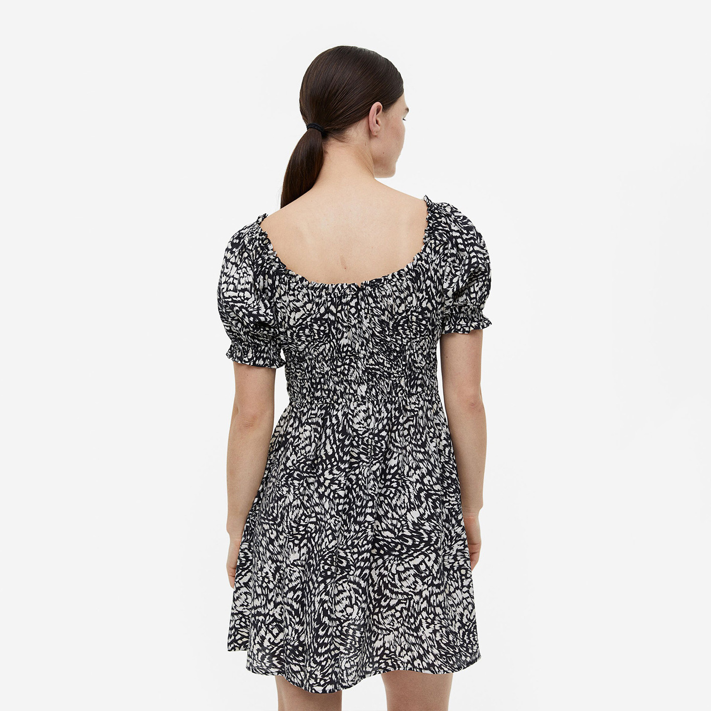 Vestido curto preto e branco com mangas bufantes e decote quadrado visto de costas