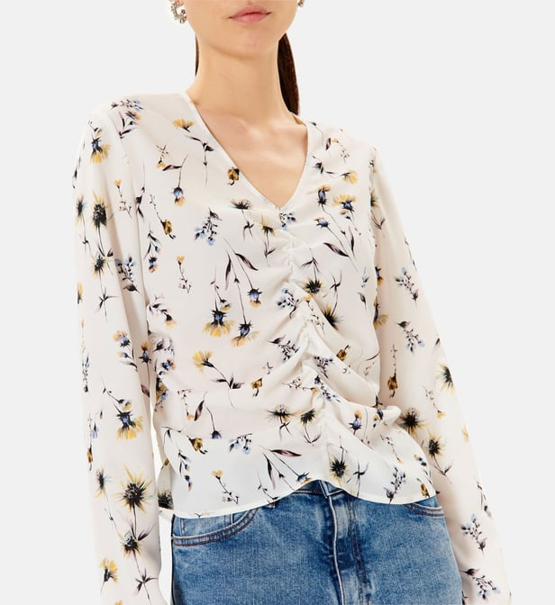 Blusa feminina branca com padrão de flores e decote em V, mangas compridas.