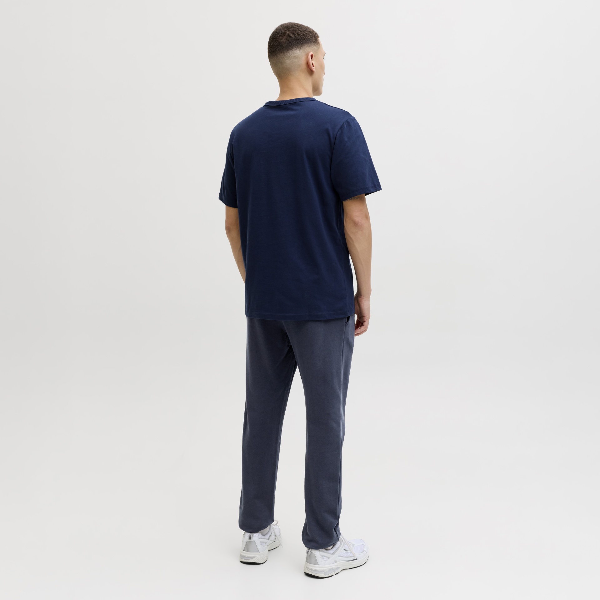 Homem de costas com t-shirt azul escura e calças de ganga azuis