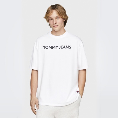 Modelo a usar t-shirt branca 'TOMMY JEANS' com calças claras em fundo branco