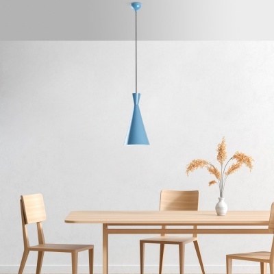 Lustre azul pendente sobre mesa de madeira com cadeiras e vaso com flores secas