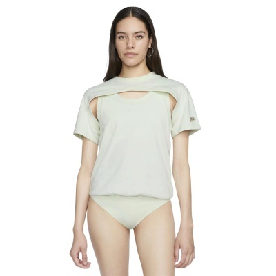 Mulher com body creme e t-shirt curta danóncio creme com logo Nike dourado na manga esquerda.