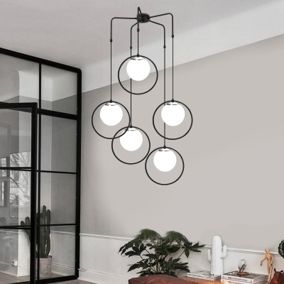 Candeeiro de teto com 5 globos brancos em armações redondas pretas suspensos numa sala moderna.