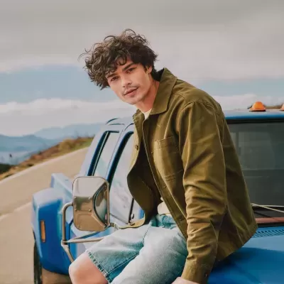 Homem com casaco verde sentado numa carrinha azul na estrada