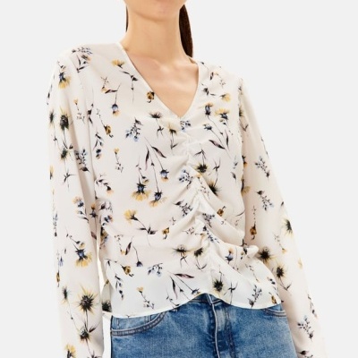 Blusa feminina branca com padrão de flores e decote em V, mangas compridas.