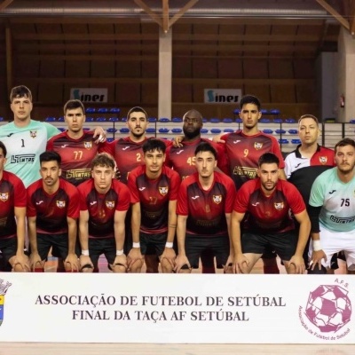 Equipa de futebol masculina posando em pavilhão com faixa da Associação de Futebol de Setúbal