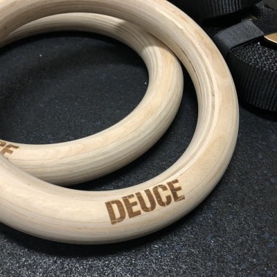 Anéis de treino em madeira clara com gravação DEUCE e correia preta ao lado