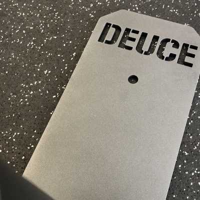 Prancha de skate cinza com 'DEUCE' em preto sobre chão escuro com pontos brancos