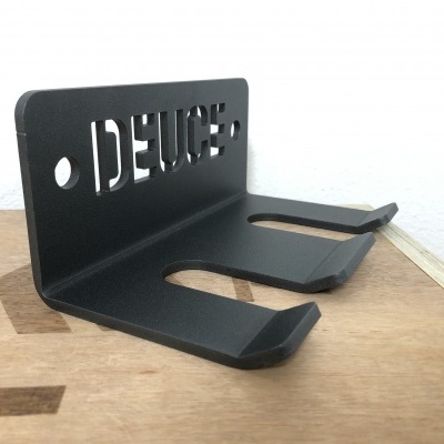 Suporte de metal preto com texto recortado DEUCE sobre superfície de madeira
