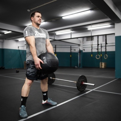 Homem com bola medicinal preta num ginásio