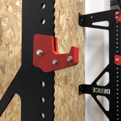 Gancho de suporte vermelho numa estrutura metálica preta com fundo de madeira