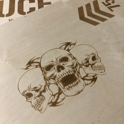 Placa de madeira com gravação de três caveiras e texto parcial