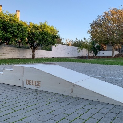 Rampa branca para skate com degraus e superfície inclinada numa área externa