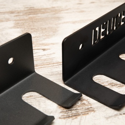 Suportes de metal preto fosco com texto recortado DELUXE sobre madeira clara