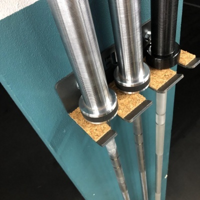 Três barras de levantamento de peso num suporte azul com proteções de cortiça