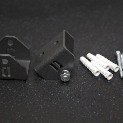 Conjunto de suportes metálicos pretos, buchas brancas e parafusos de aço numa superfície preta