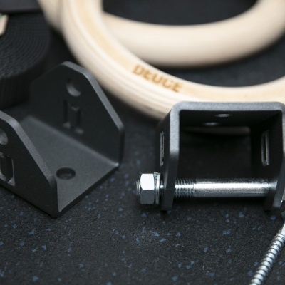 Anéis de madeira claros com acessórios metálicos pretos e parafusos sobre fundo escuro