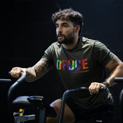 Homem em tshirt verde com texto colorido em bicicleta de exercício