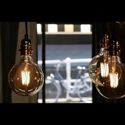 Lâmpadas pendentes de vidro transparente com filamentos, em interior com janela e bicicleta ao fundo
