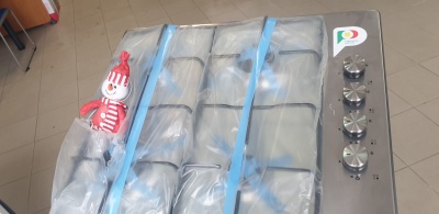 Fogão de encastre em aço inox com proteção plástica, botões metálicos e boneco decorativo ao lado