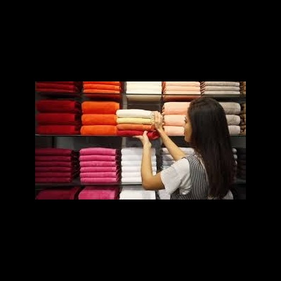 Mulher organizando toalhas coloridas empilhadas numa prateleira