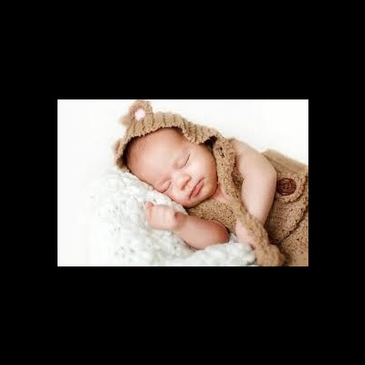 Bebé a dormir vestindo fato castanho de malha com orelhas, sobre manta branca