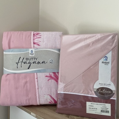 Pacote de lençóis cor-de-rosa com texto e embalagem sobre móvel
