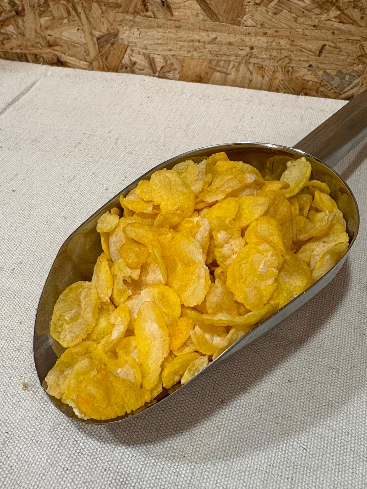 Corn Flakes 100% Milho Pá metálica com flocos de cereais de milho amarelos sobre tecido branco