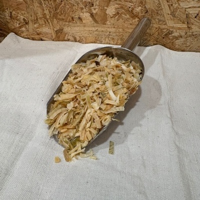 Pá metálica com aparas de madeira sobre tecido branco e fundo de madeira.