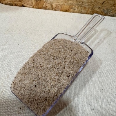 Pá transparente cheia de pó marrom claro sobre tecido claro e fundo de madeira