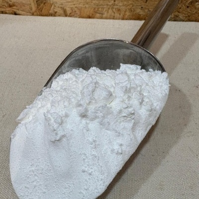 Pá metálica com pó branco sobre tecido bege e fundo de madeira OSB