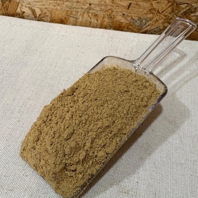 Colher de plástico com pó marrom claro sobre tecido bege