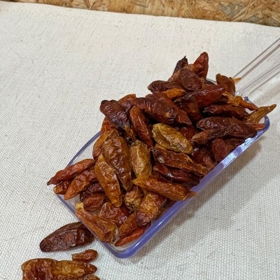 Pá transparente com malaguetas secas castanhas sobre toalha de linho branca