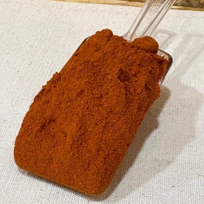 Pá de plástico com pó castanho avermelhado sobre tecido creme