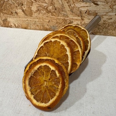 Fatias secas de laranja em colher de metal sobre tecido branco com fundo de madeira OSB