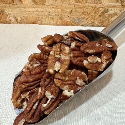 Pecãs em concha metálica sobre superfície clara com fundo de madeira