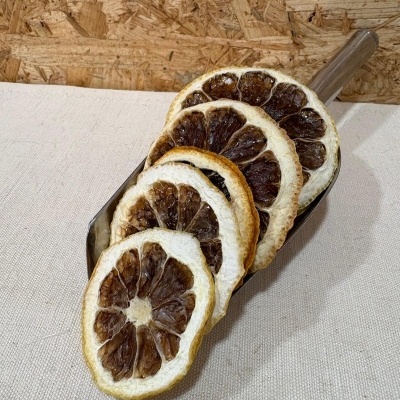 Fatias secas de limão marrons e brancas em concha metálica sobre tecido cru