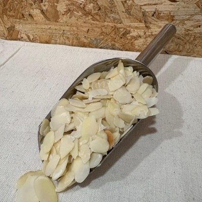 Pá metálica com amêndoas laminadas sobre tecido bege claro