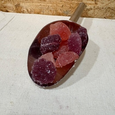 Colher metálica com doces de goma vermelha e rosa cristalizados em açúcar